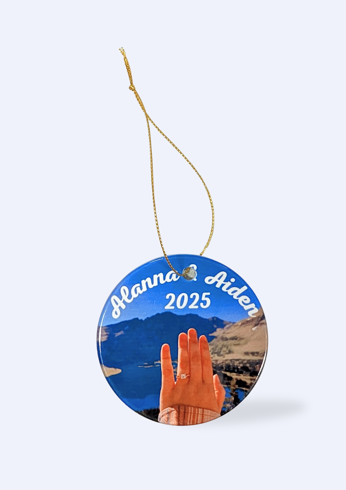 A photo of a customized circular ornament hanging on a gold thread against a white background.