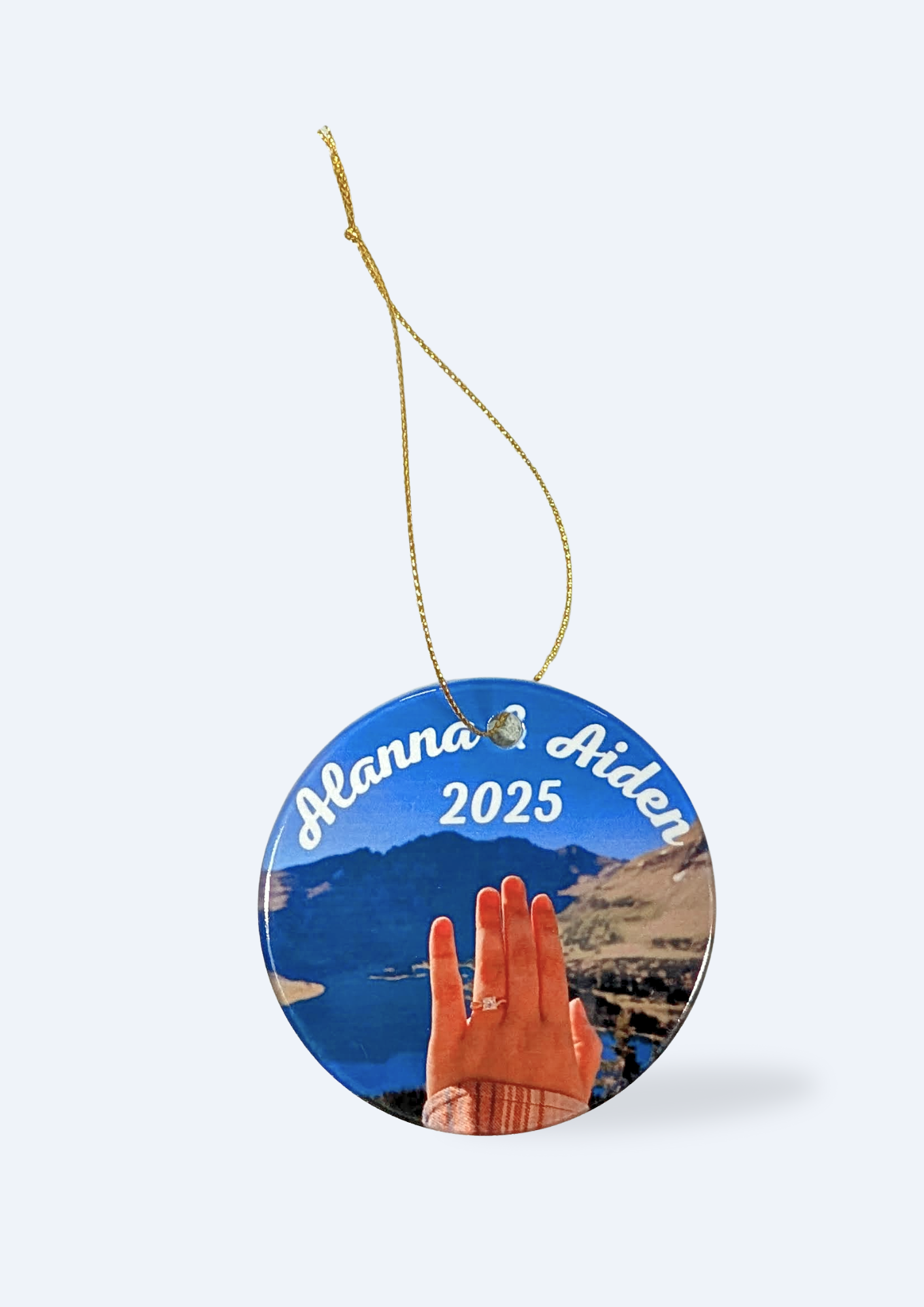 A photo of a customized circular ornament hanging on a gold thread against a white background.